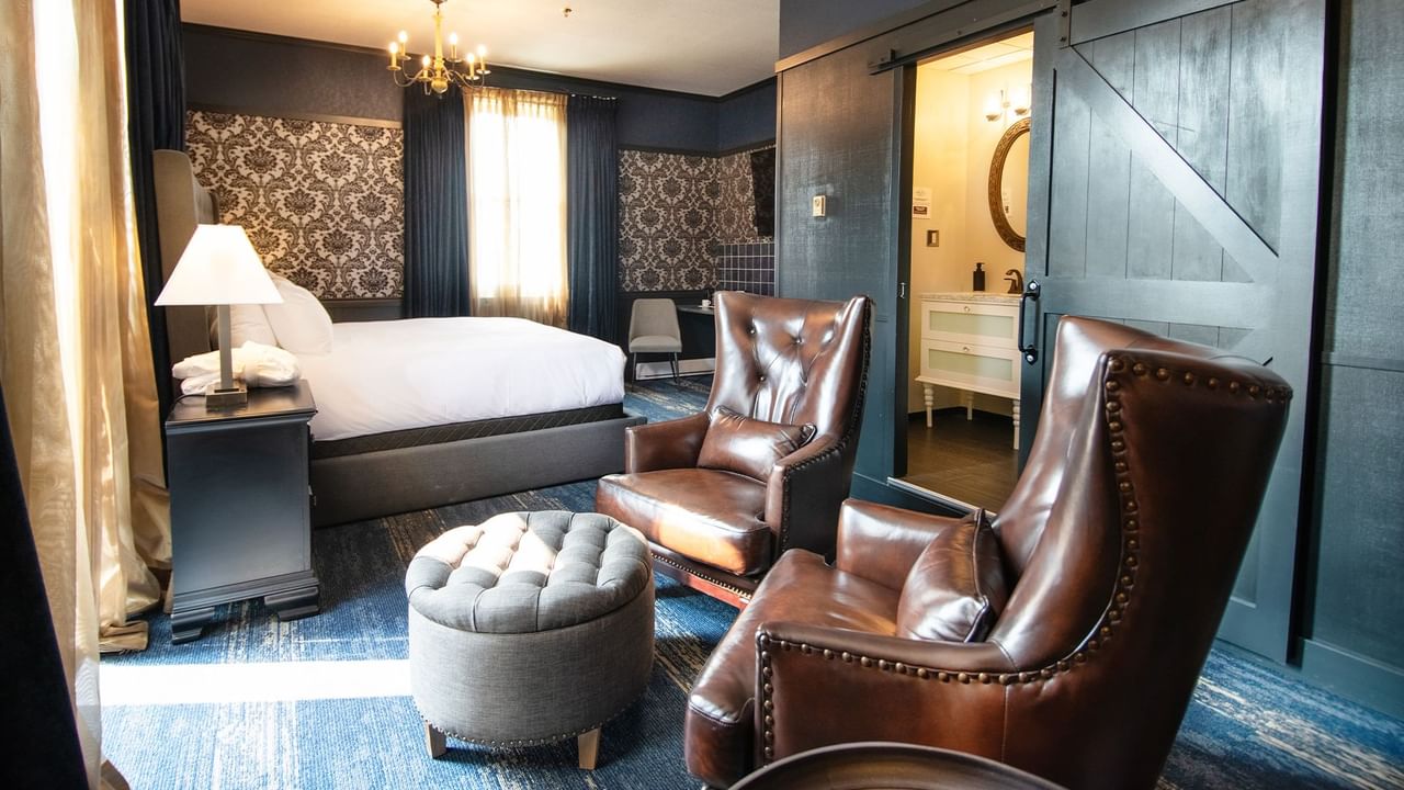 Hotel room with king bed, armchair, lamp, night stand, and washroom