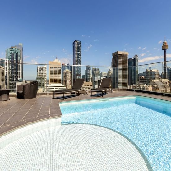 Rooftop pool area & loungers with a city view at Pullman Sydney Hyde Park