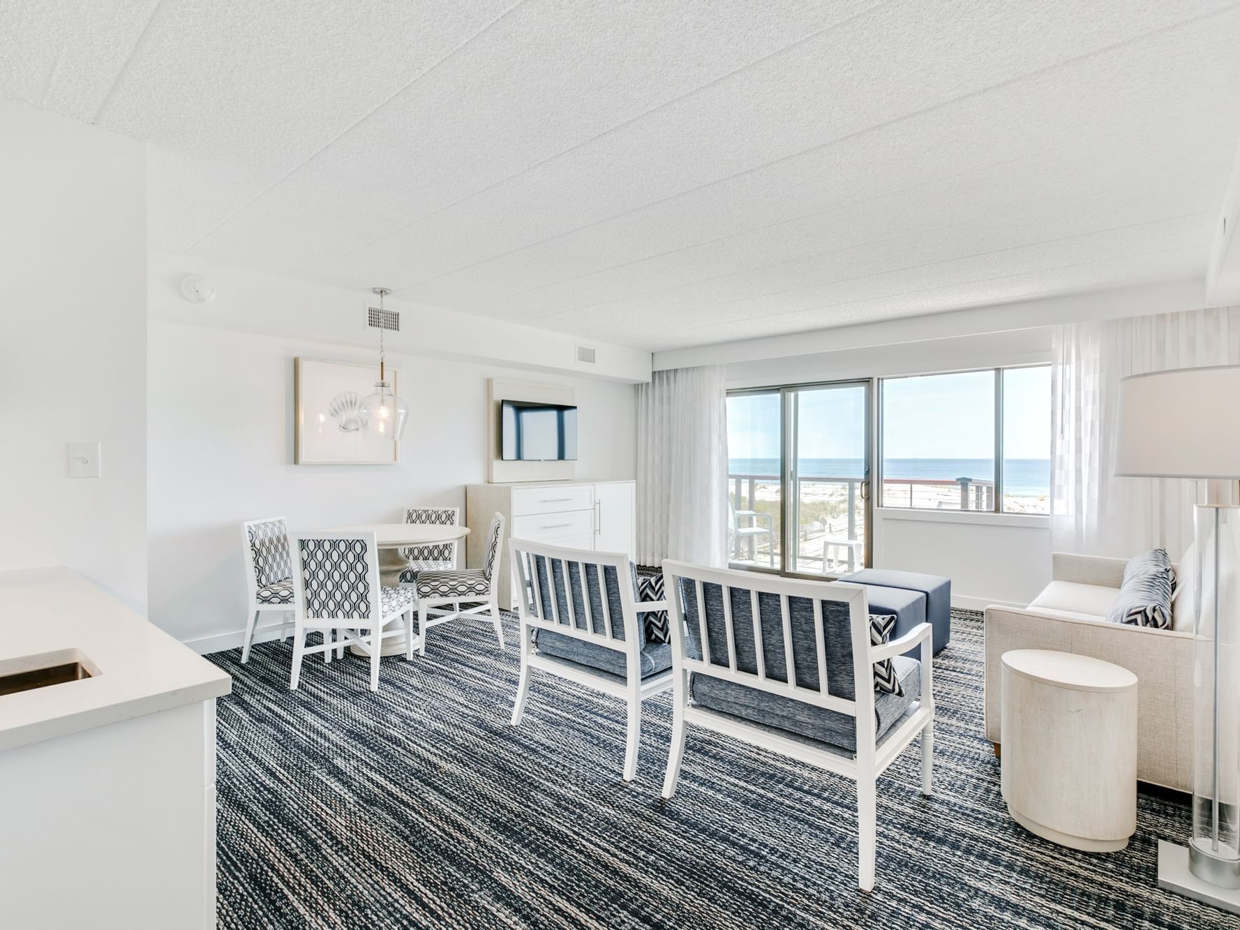 Oceanfront 1 Bedroom Suite at ICONA Windrift Resort with Living area with pull out couch, sitting chairs, and dining table
