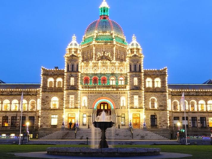 Illuminated Victoria building with central fountain at night for Winter in Victoria Getaway offer.