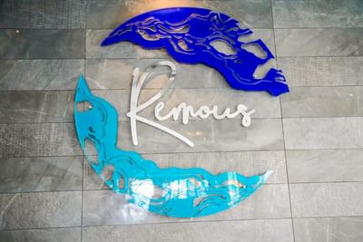 Remous signage in script font between blue and teal wave motifs on a grey tiled wall at The Abidah Hotel by Accra