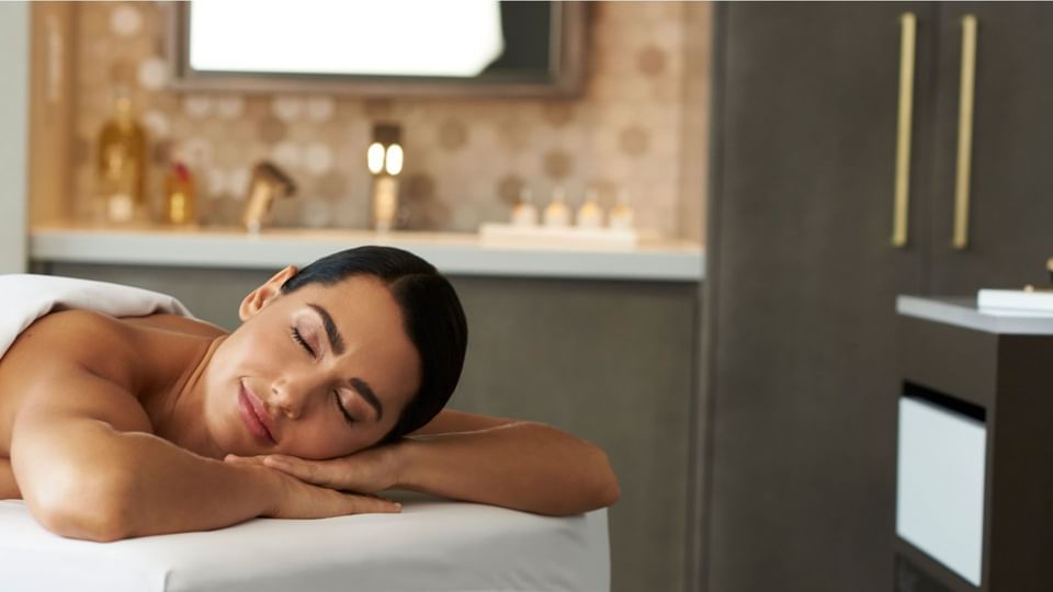 Guest relaxing on a massage table in a peaceful treatment room during a soothing wellness experience at Hotel X Toronto