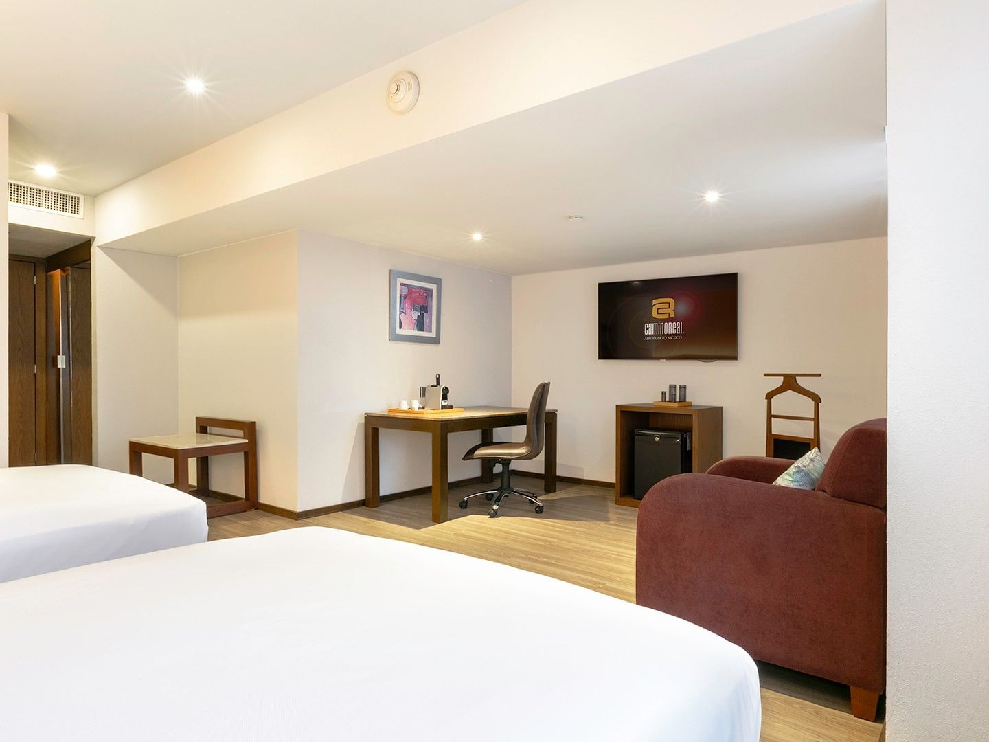 Habitación Junior Suite con 2 camas dobles, televisión y mesa de trabajo en Camino Real Aeropuerto México, Ciudad de México