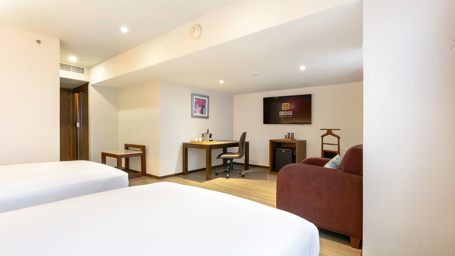 Habitación Junior Suite con 2 camas dobles, televisión y mesa de trabajo en Camino Real Aeropuerto México, Ciudad de México