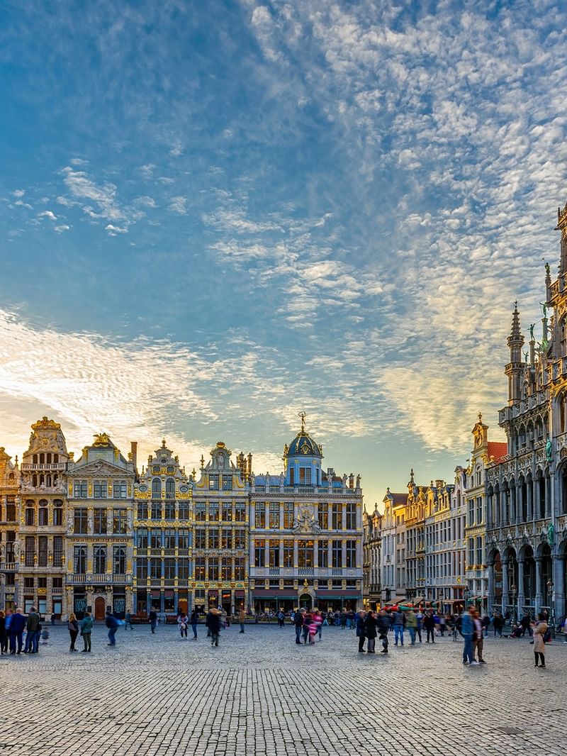 Grand Place square with tourists and Belgian flag in Brussels.