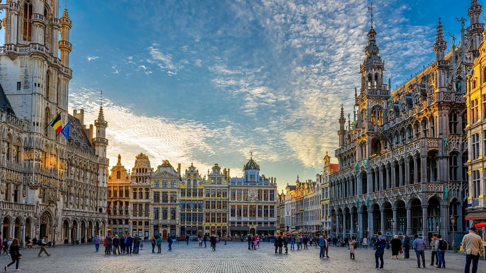 Grand Place square with tourists and Belgian flag in Brussels.