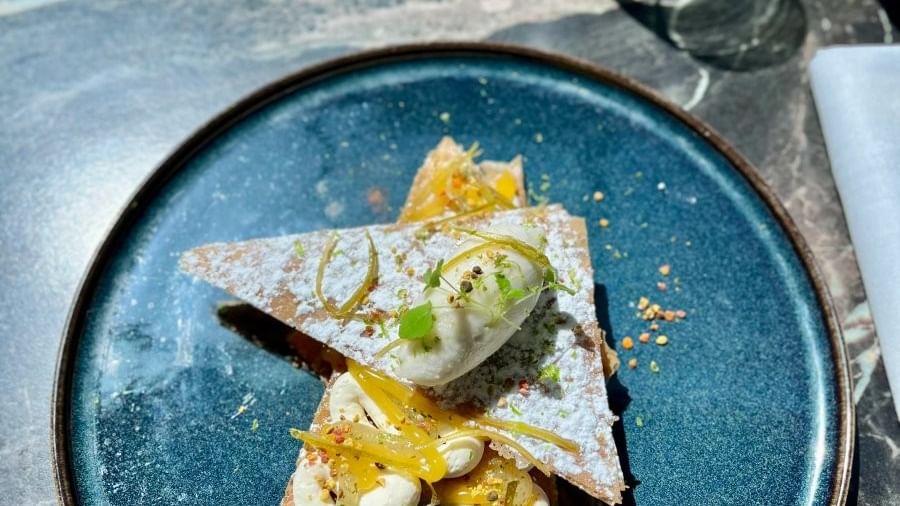 Dessert en étoile sur assiette bleue avec café et verres à vin sur table en marbre.