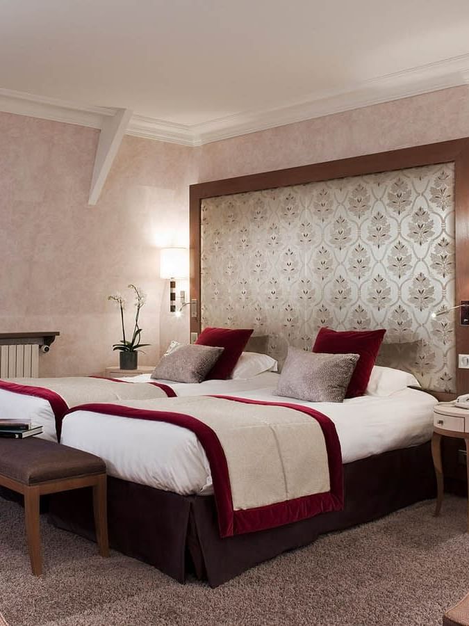 Cozy bench by twin beds with wooden bedside table in Suite Junior at Le Grand Hôtel des Thermes