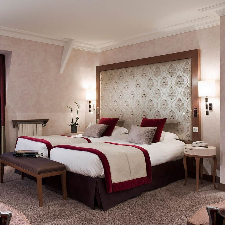 Cozy bench by twin beds with wooden bedside table in Suite Junior at Le Grand Hôtel des Thermes