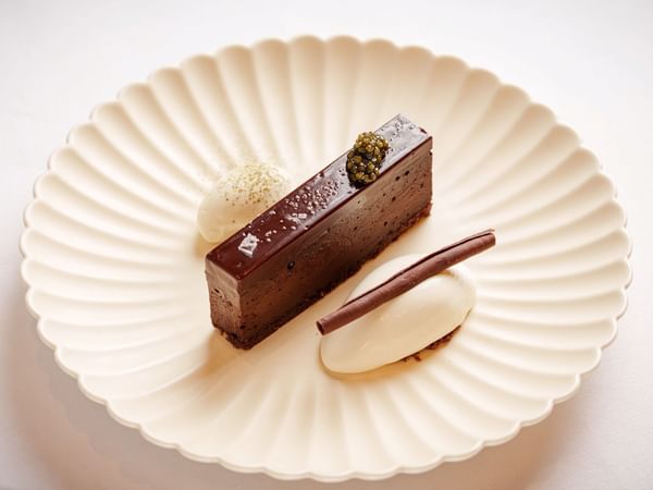 Chocolate cake with a berry and white mousse on a scalloped plate at The Capital Hotel, Apartments & Townhouse.