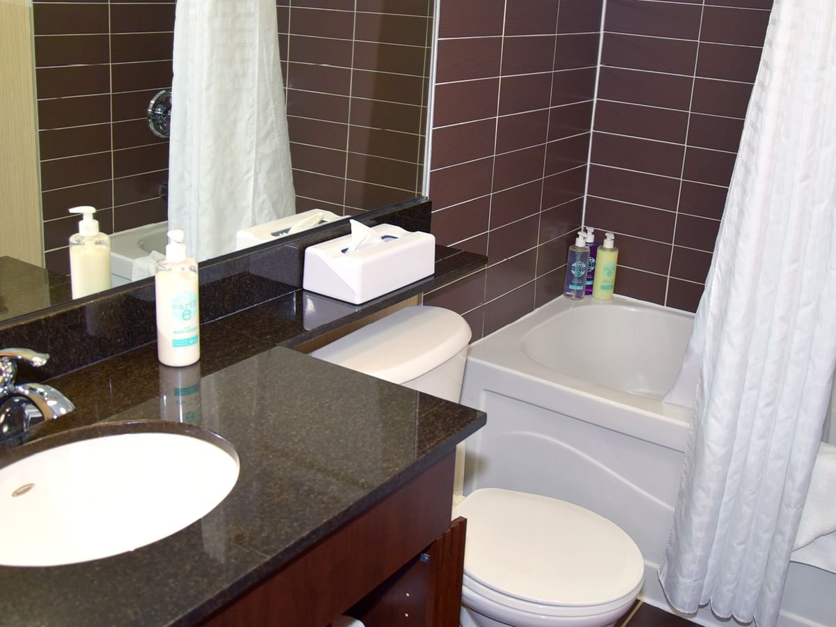 A bathroom with a sink, toilet, bathtub, and white shower curtain.