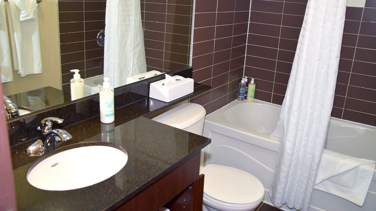 A bathroom with a sink, toilet, bathtub, and white shower curtain.