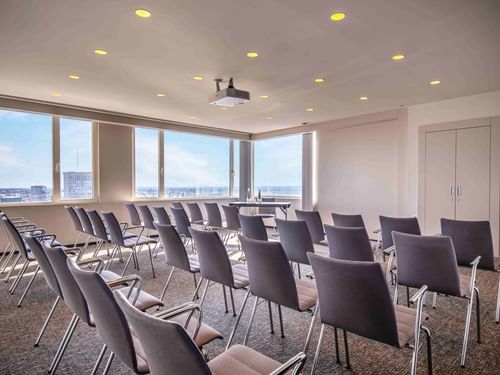Meet 26 Two meeting room with rows of gray chairs and large windows offering a city view at The Hotel Brussels
