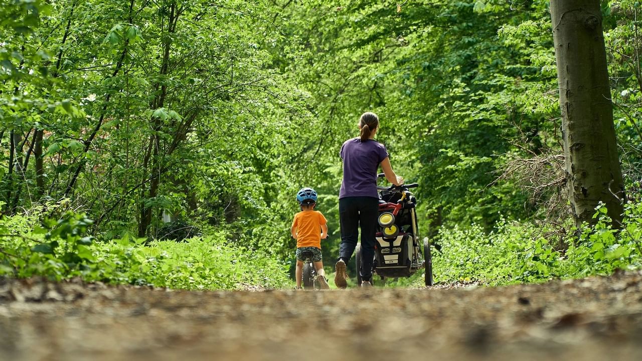 Mother and child walking on trail through lush greenery