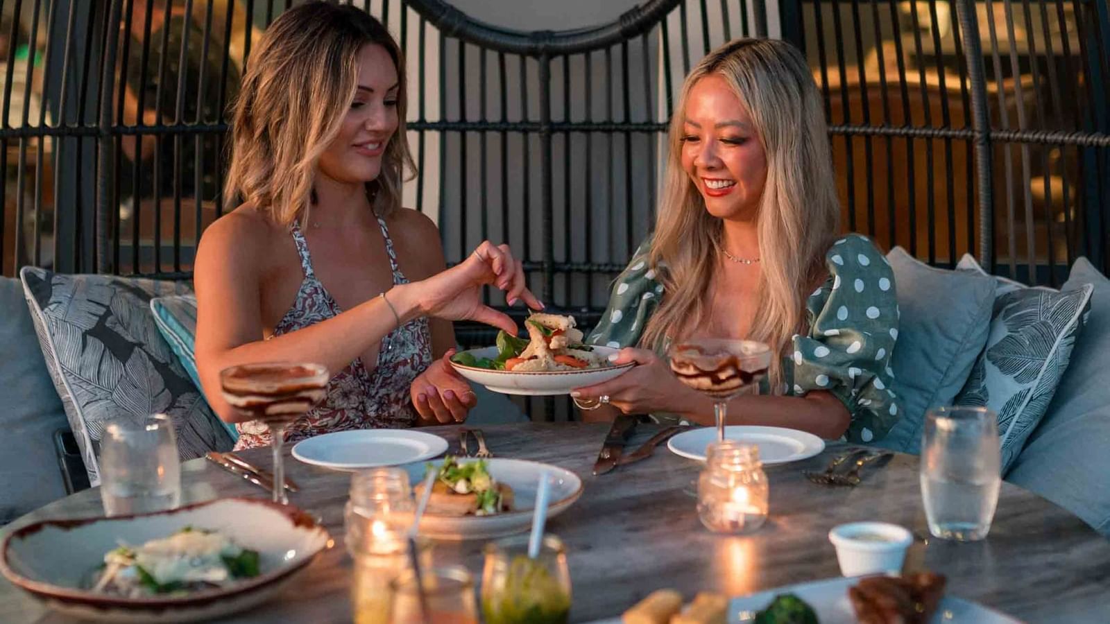Two individuals dining with dishes and drinks, in Karinyas Restaurant at Mercure Kooindah Waters