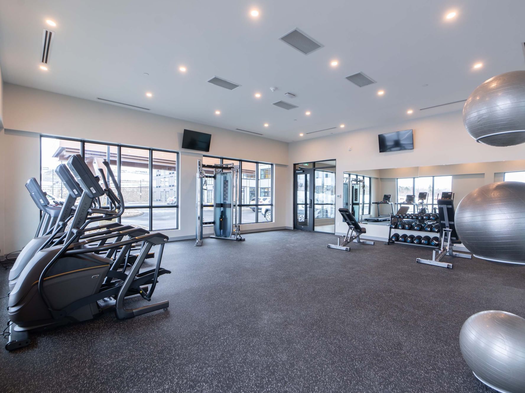 Ellipticals and, multifunction machines by the window in the Fitness center with carpet floor at Sandman Signature Las Colinas