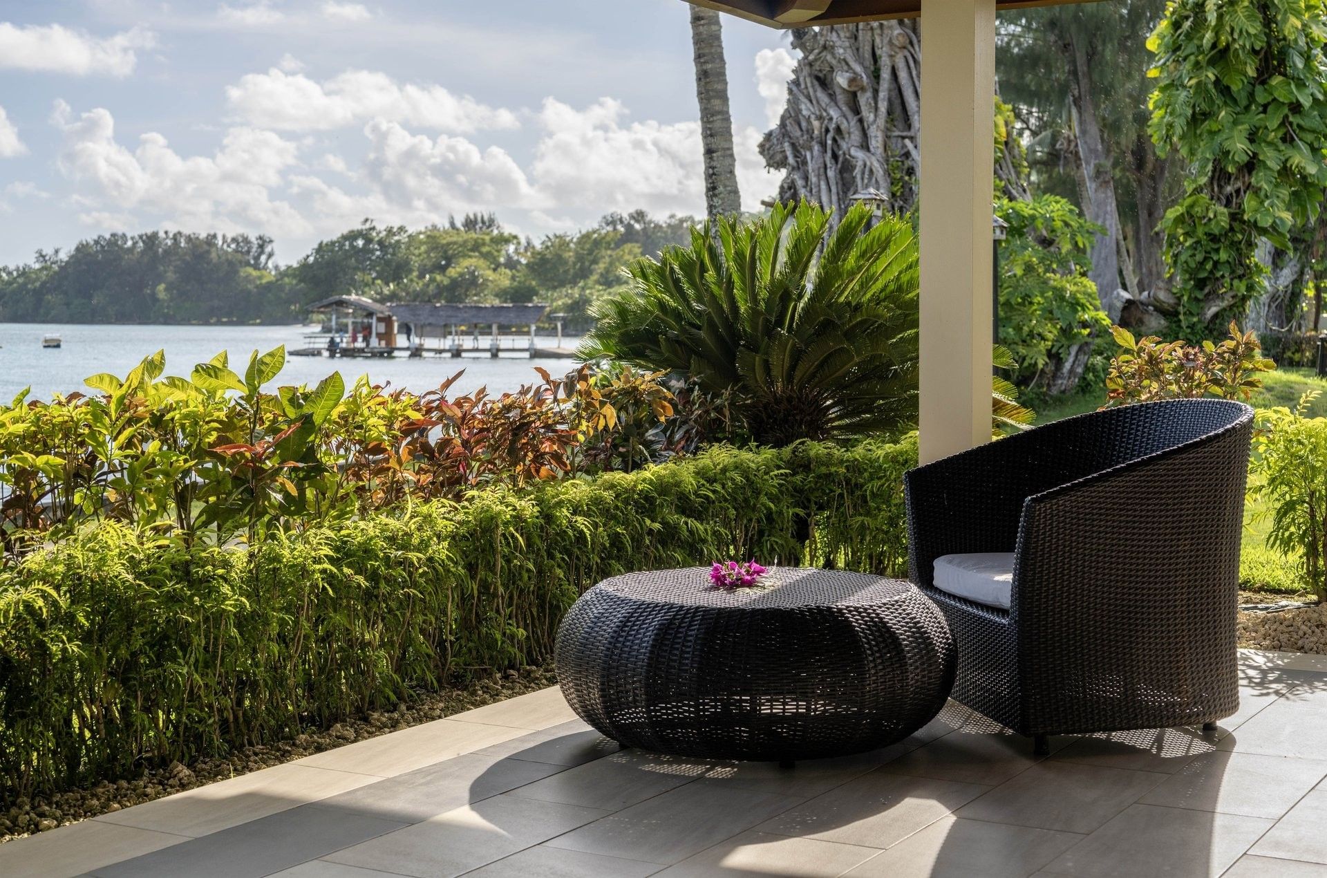 Relaxing outdoor terrace with black wicker furniture overlooking a calm lake in Erakor Residence at warwick le lagon-vanuatu