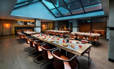 Charcoal’s modern interior with wooden tables, leather chairs, and a glass ceiling at The Saujana Hotel Kuala Lumpur