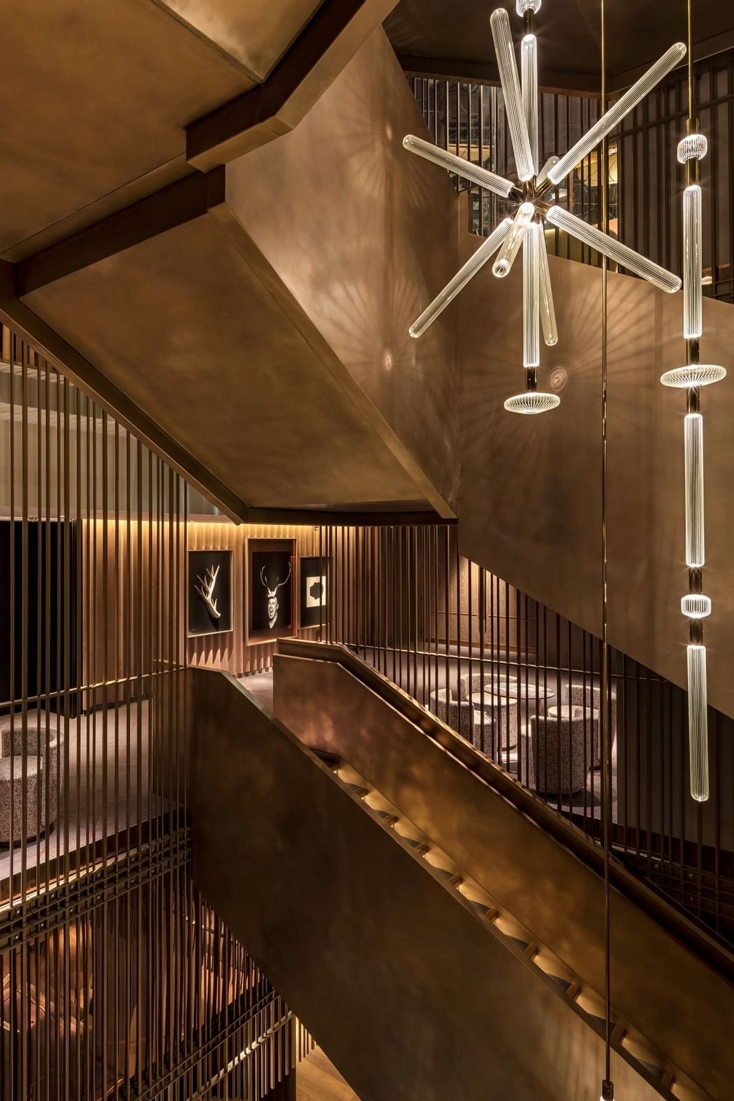 A luxurious staircase at The Londoner Hotel, featuring modern lighting, a golden sculpture, and elegant railings