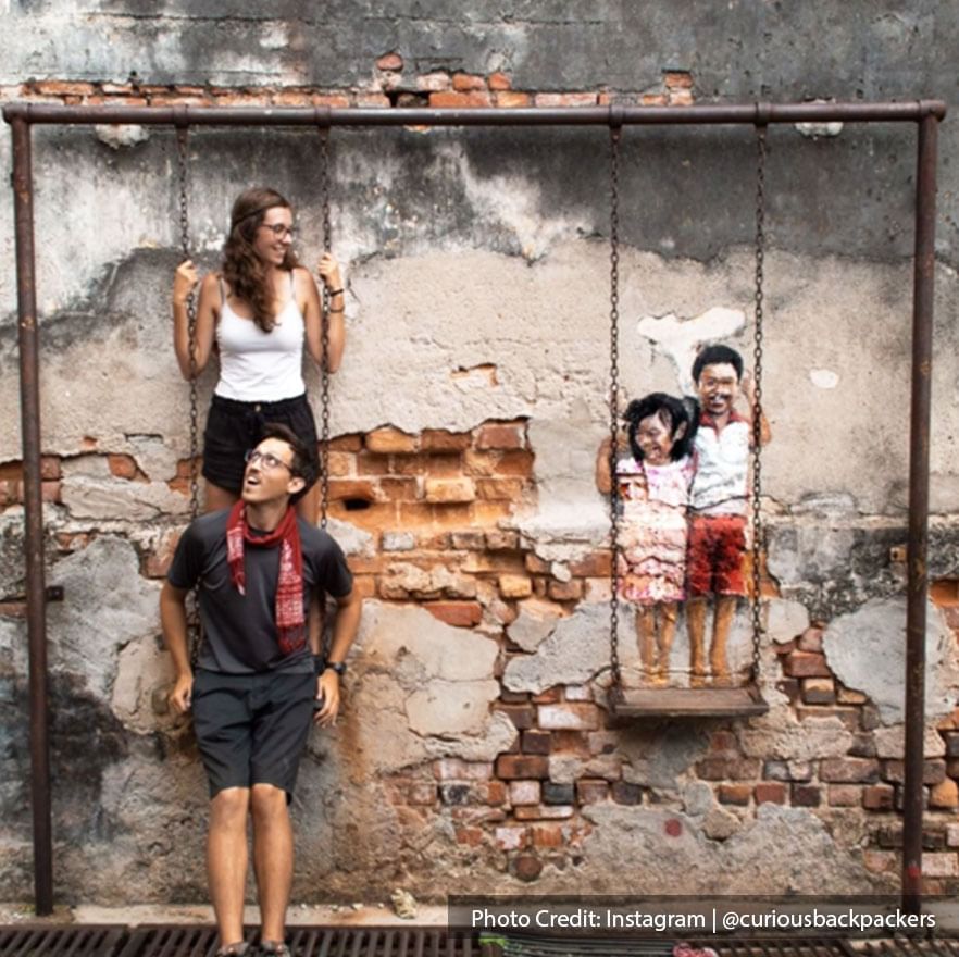 Siblings on a swing mural art in Penang by local artist Louis Gan.