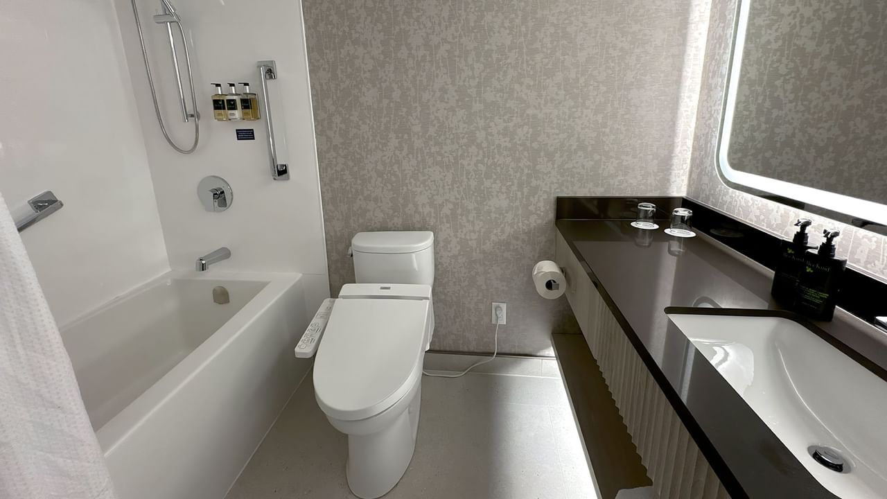 Hotel washroom with TOTO washlet, bathtub, sink, soap, towels and mirror