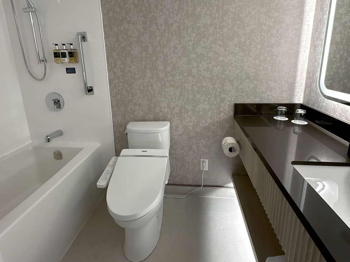 Hotel washroom with TOTO washlet, bathtub, sink, soap, towels and mirror