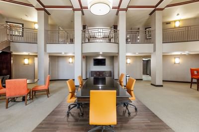 Long black conference table with orange chairs in a spacious, two-story hotel atrium in Open Area at Branson Hillside Hotel