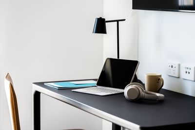 Laptop, headphones & drink on a work desk at Nesuto Docklands