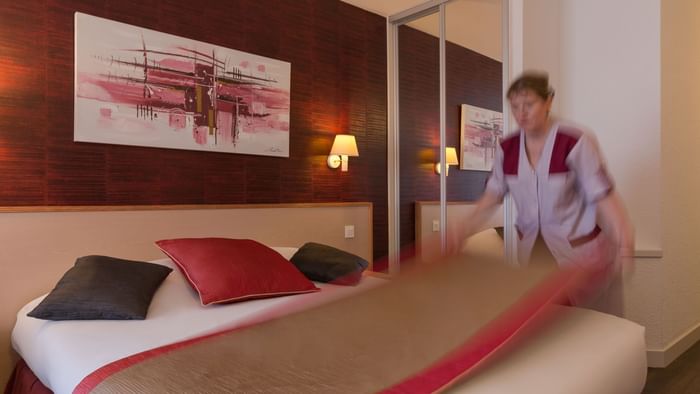A maid preparing a Standard Double bed at Hotel L'Arc-En-Ciel