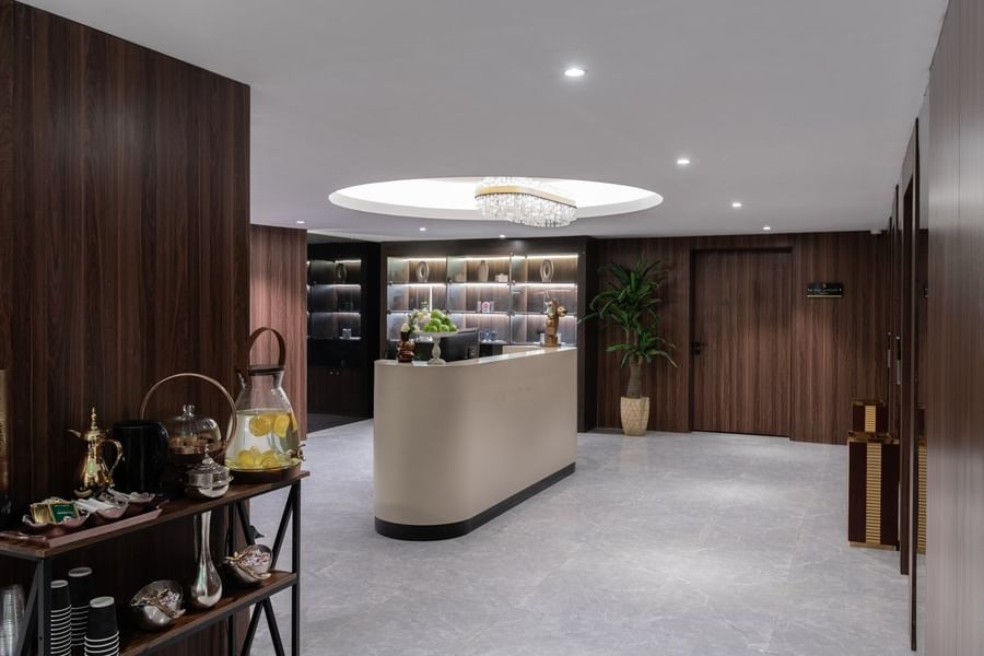 Curved reception desk with wood panels under a crystal chandelier at Warwick Al Taif Hotel