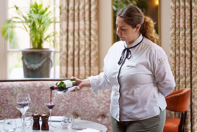 A Staff member pouring wine into a glass at Richmond Hill Hotel