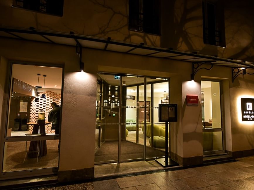 Entrée éclairée d'un hôtel de nuit avec un client à l'intérieur, Hôtel Rivella.