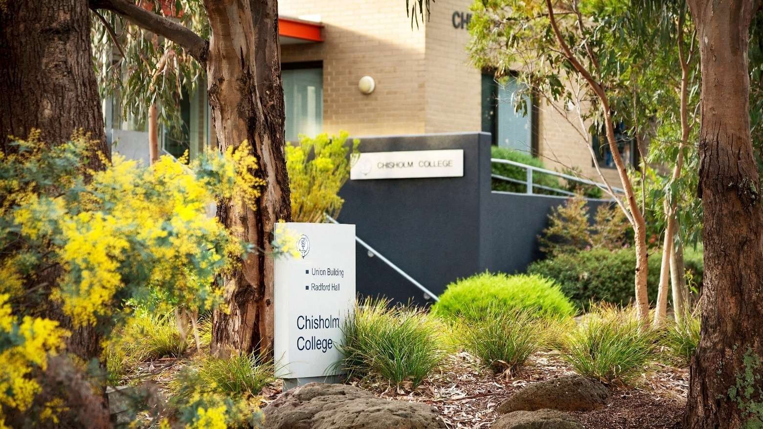 Sign for Chisholm College in front of the Union Building and Radford Hall at La Trobe University.
