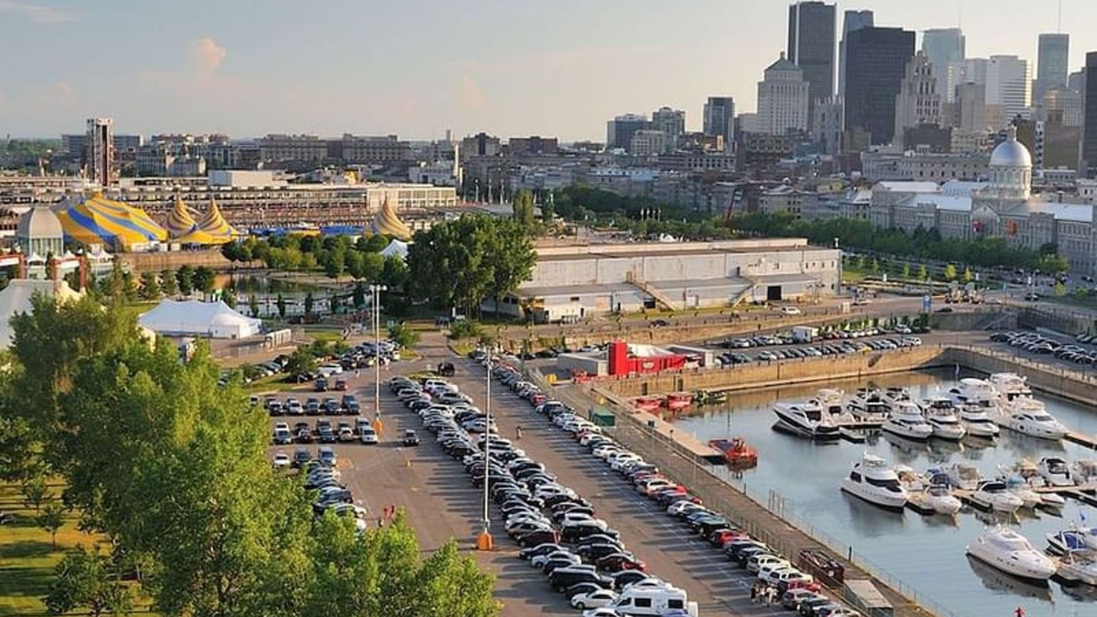 Aerial view of a boat harbor and parking lot by the city skyline near Warwick Le Crystal Montreal