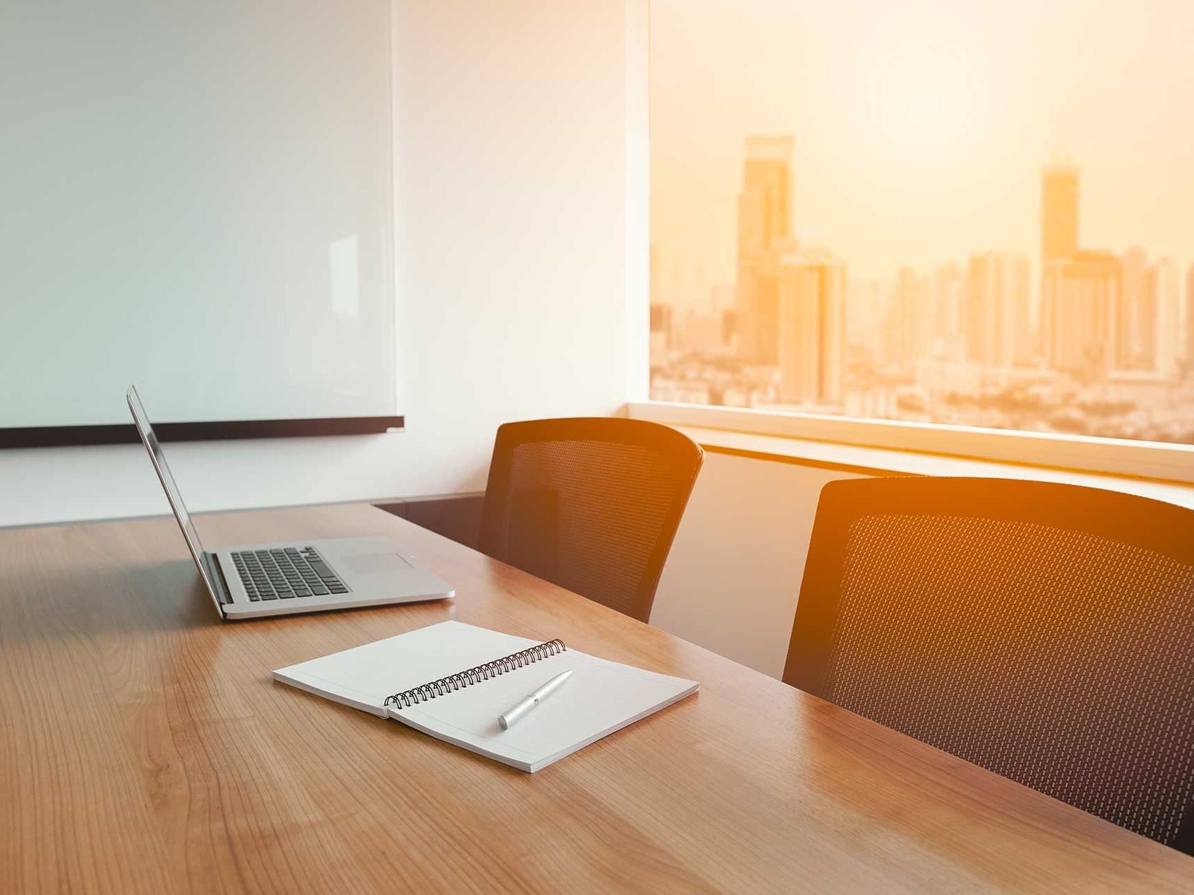 Laptop & a notebook are on a meeting table at Momentus Hotel