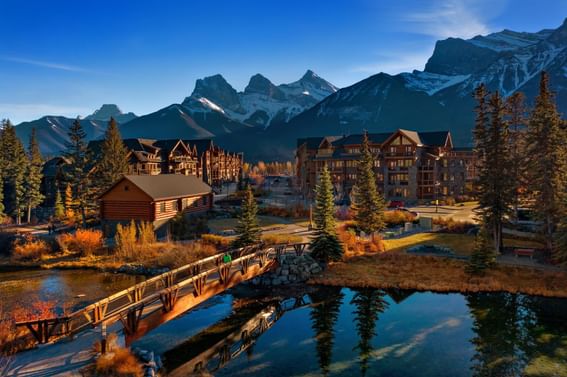 Aerial view of Spring Creek Vacations with cabins, a bridge over a pond and a mountain backdrop