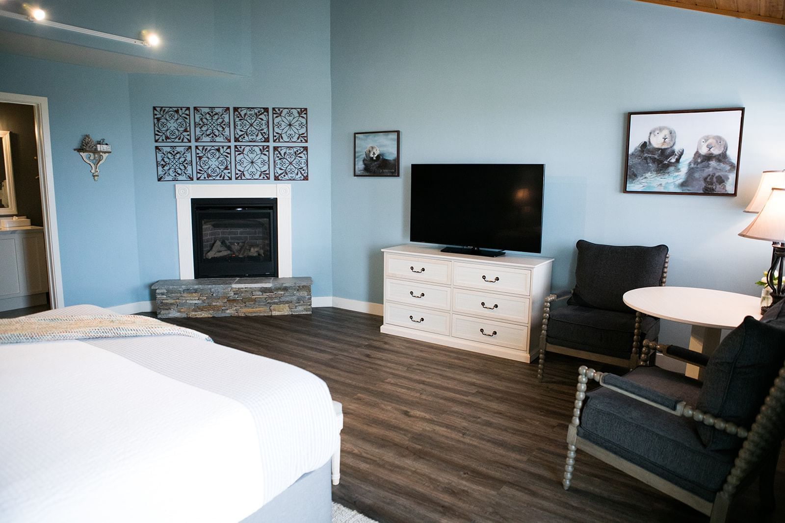 A hotel room with a king-sized bed, fireplace, TV, and sitting area.