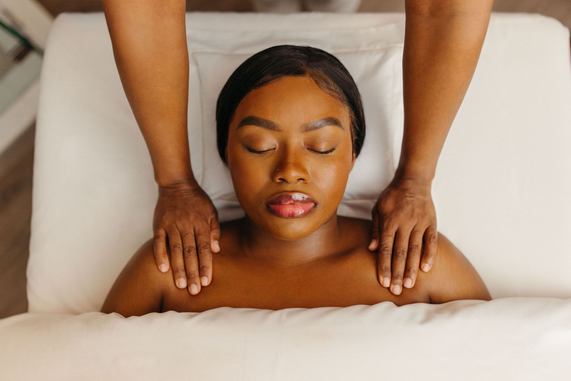 Woman receiving a relaxing shoulder massage with therapist hands resting on shoulders at Guerlain Spa at Hotel X Toronto