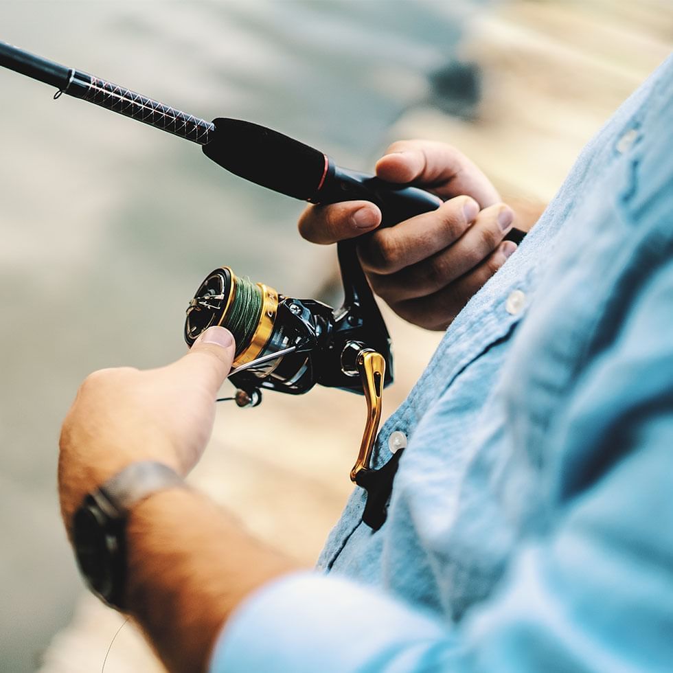 Person holding a fishing rod focusing on the reel & line near Falkensteiner Hotel & Spa Carinzia