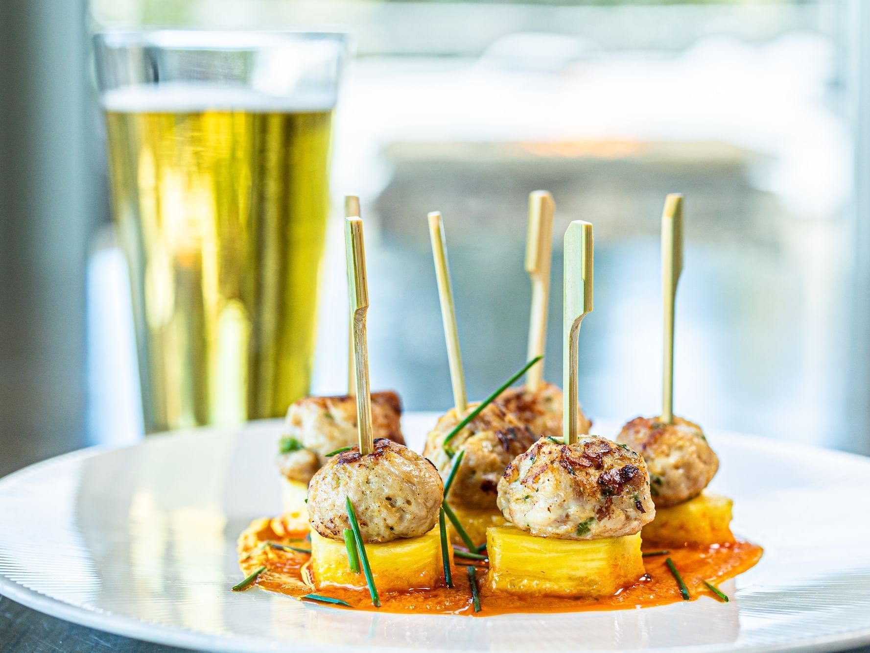 A plate of food with toothpick skewers and a glass of beer in 7880 Club at Stein Eriksen Residences