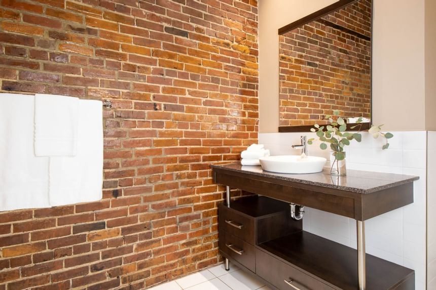 Bathroom vanity, towel rack & brick wall in Queen Premiere Chardonnay at Retro Suites Hotel