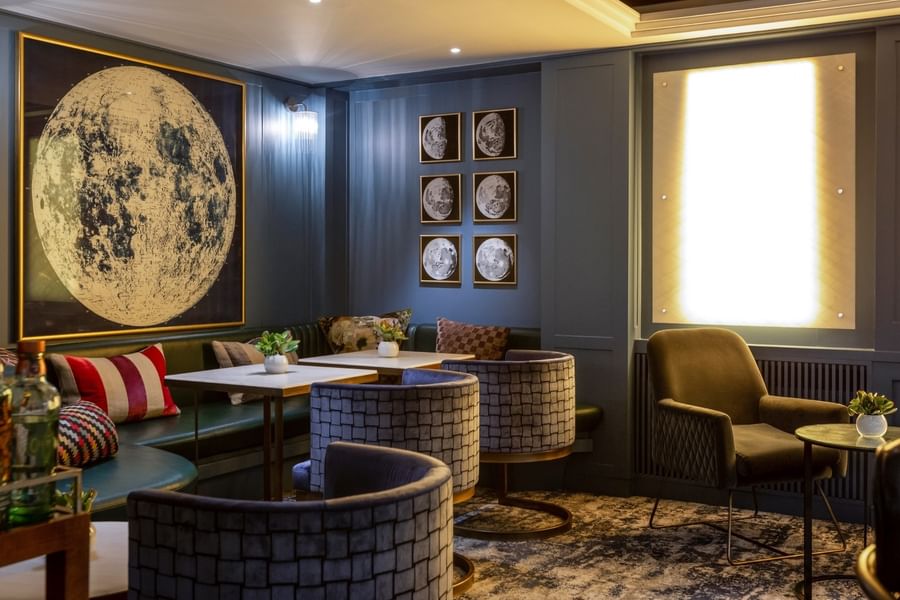 Capital Bar with chairs and tables by green sofas under moon art at The Capital Hotel, Apartments and Townhouse