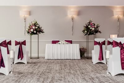 Ballroom wedding ceremony room at The Aberdeen Altens Hotel with chairs in white covers and fuchsia ribbons