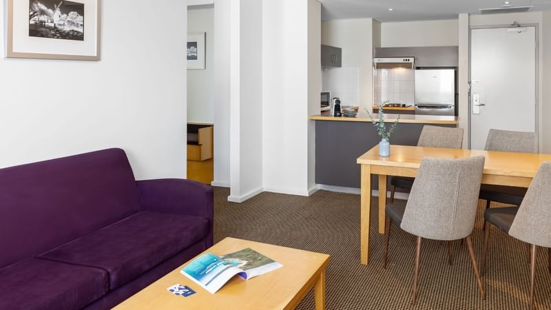 Living room area in an Apartment at Novotel Perth Langley with dining table, sofa, TV and a work desk
