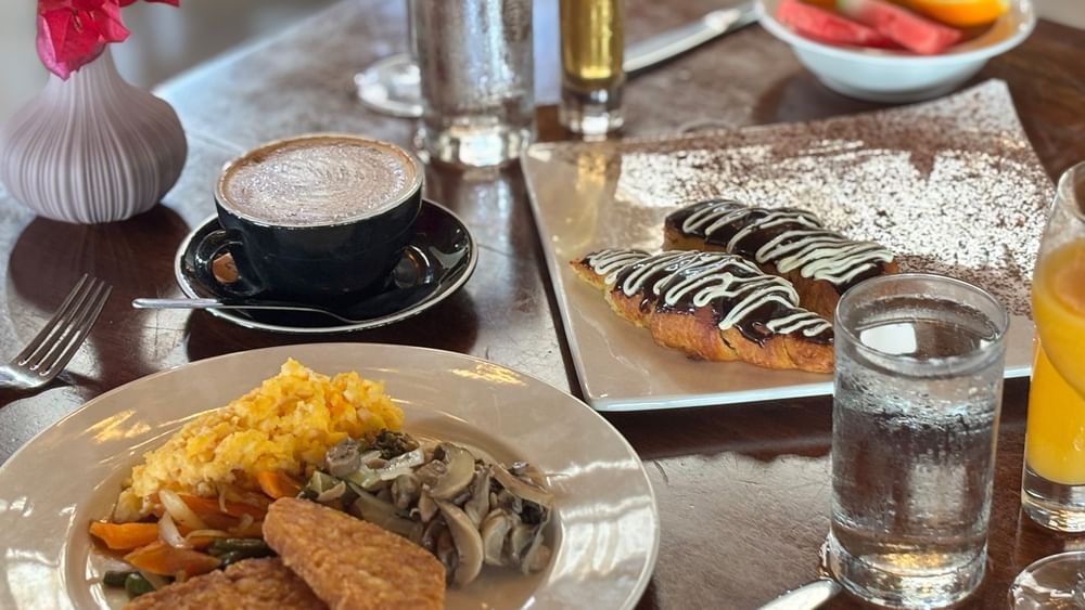 Breakfast dishes and drinks on a wooden table at Lagoon Terrace Restaurant in Efate at Warwick Le Lagon - Vanuatu.
