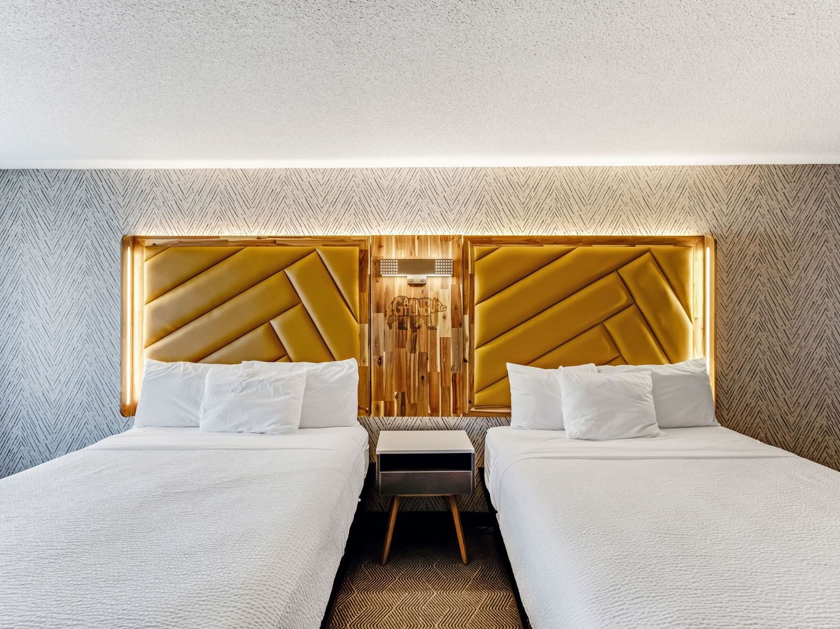 Beds with a nightstand in 2 Queen Bed Deluxe with Private Balcony at the Wander Hotel