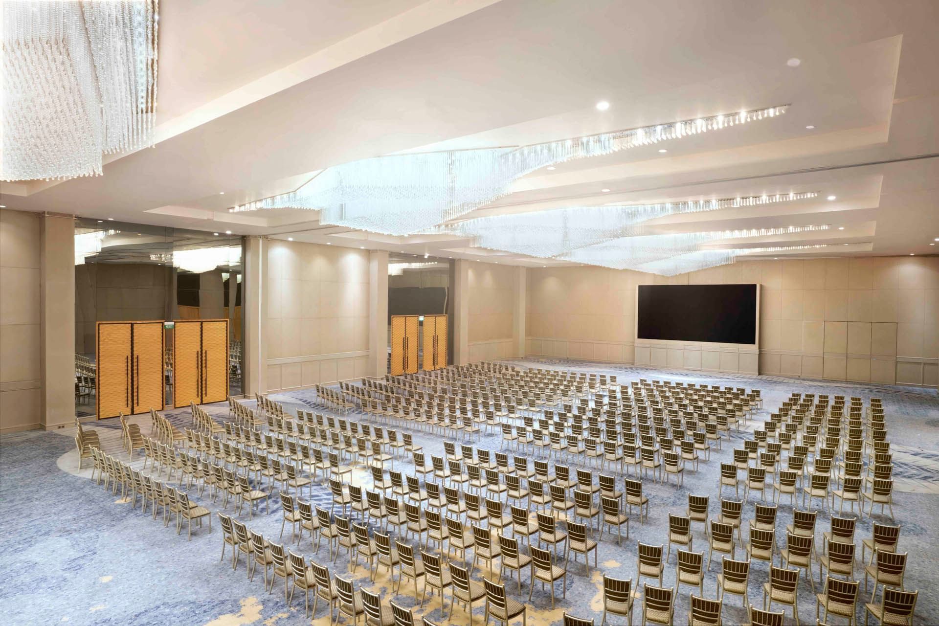 Aerial view of ballroom with arranged chairs in rows and large screen at Vasa Hotel Surabaya