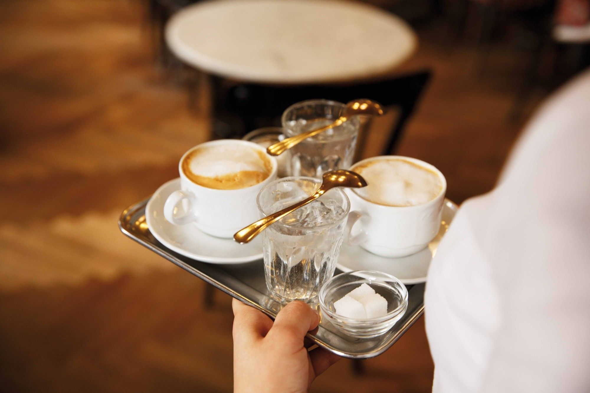 Coffee at Café Sperl in Vienna with glasses of water, sugar and classic golden spoons on a serving tray