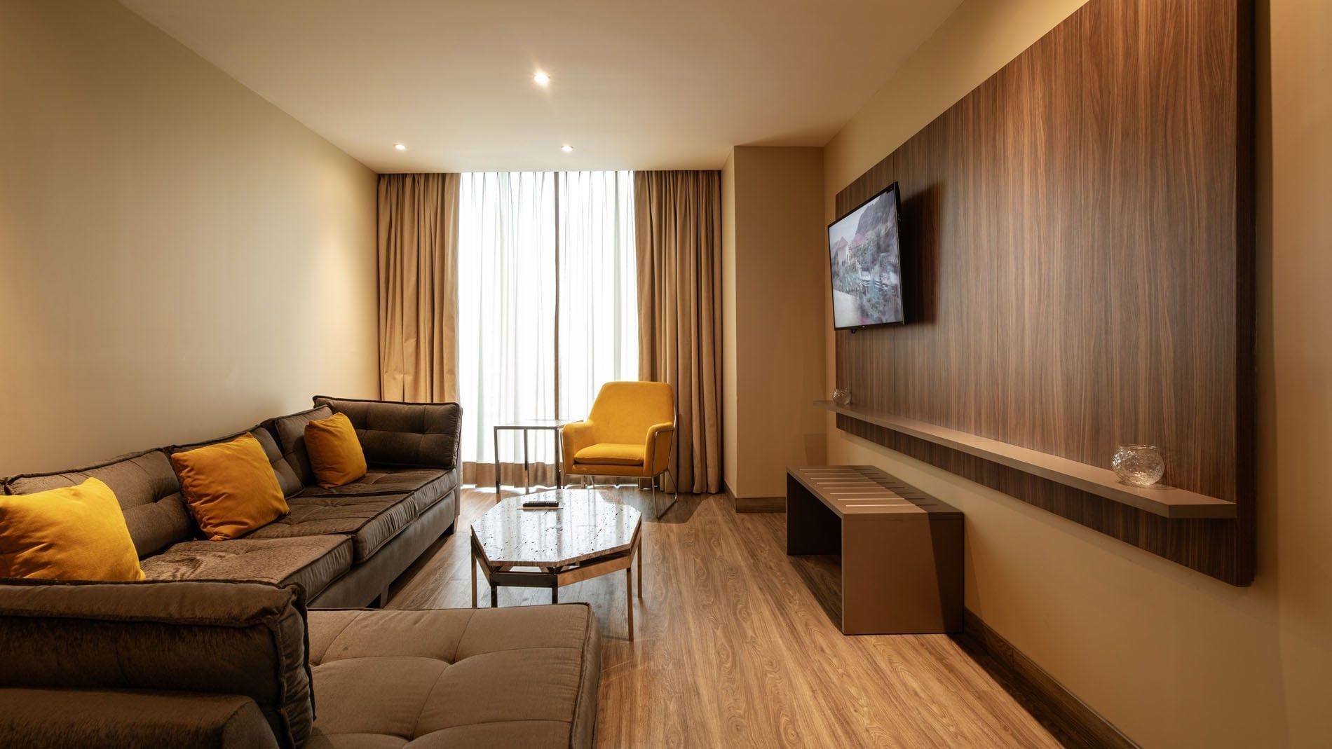 King Master Suite with brown furniture, yellow cushions, a TV, and a glass table at Camino Real