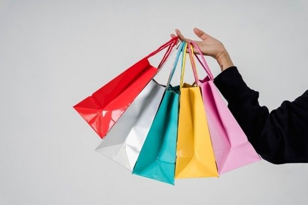 Several shopping bags being carried while out shopping.